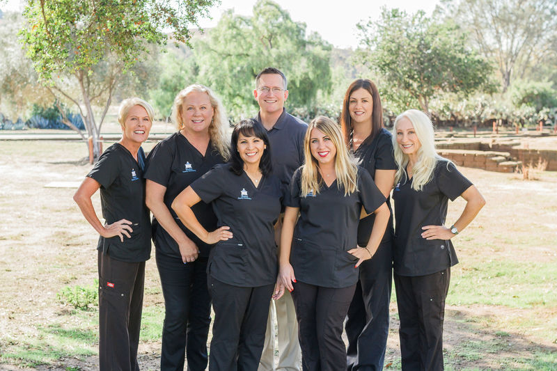 photo of the dentist and team outside in a field with trees in the background